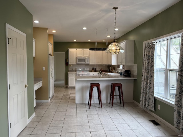 kitchen featuring white appliances, light tile patterned floors, light countertops, a peninsula, and visible vents