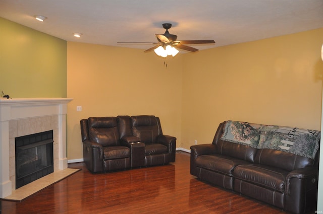living area with wood finished floors, a tile fireplace, baseboards, and ceiling fan