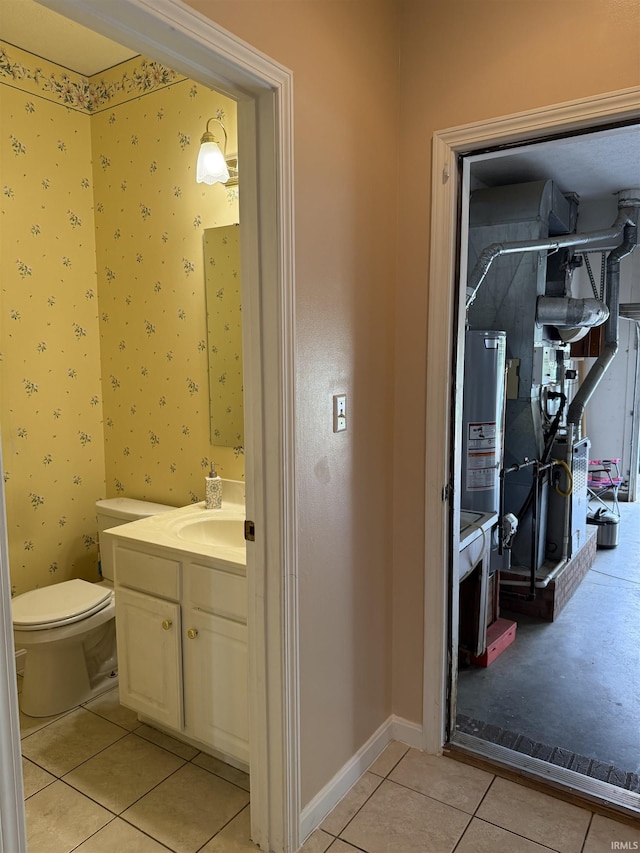 bathroom featuring vanity, toilet, tile patterned flooring, and water heater