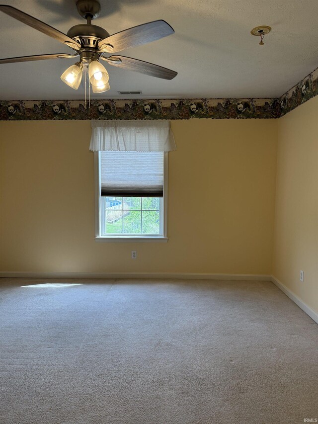 carpeted spare room featuring baseboards, a ceiling fan, and visible vents