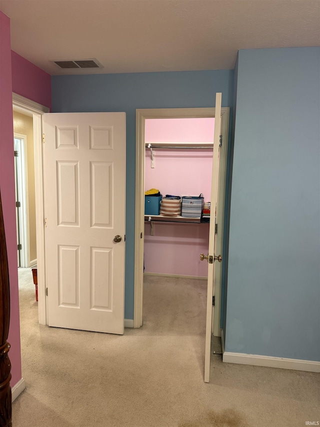 unfurnished bedroom featuring baseboards, carpet flooring, and visible vents