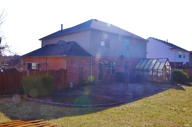 rear view of house featuring fence, a patio area, a greenhouse, an outdoor structure, and a yard