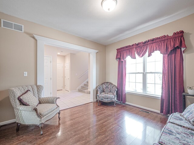sitting room with baseboards, visible vents, wood finished floors, and stairway