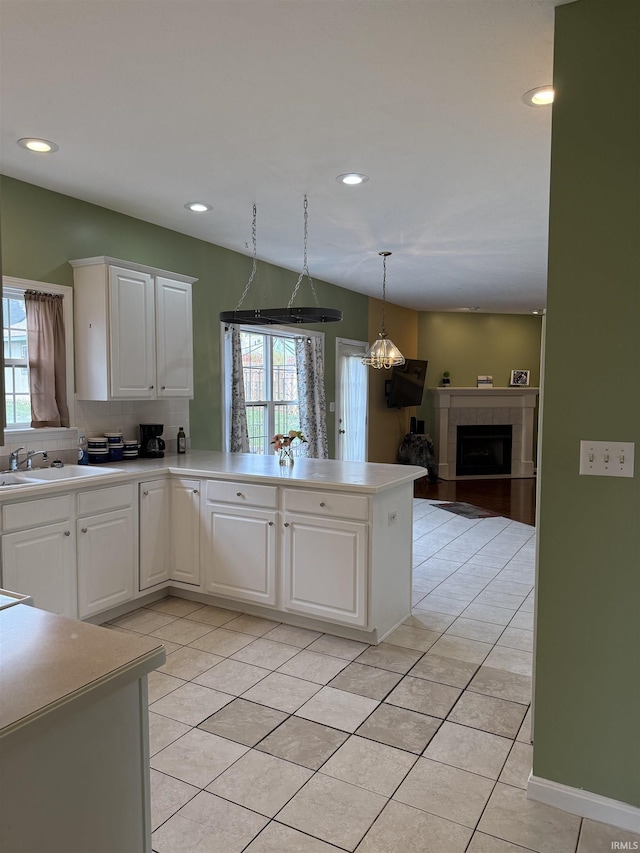kitchen with plenty of natural light, a peninsula, a sink, and light tile patterned floors
