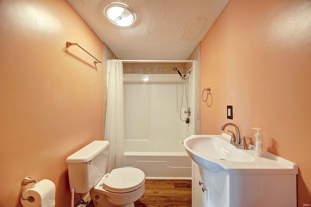 bathroom featuring a textured ceiling, toilet, shower / tub combo with curtain, wood finished floors, and vanity