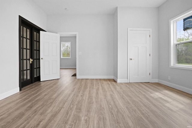 empty room with light wood-type flooring, a wealth of natural light, and baseboards