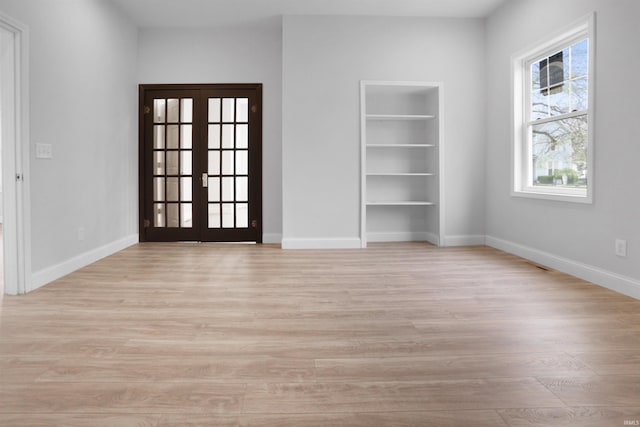 interior space featuring light wood-type flooring, french doors, baseboards, and built in shelves