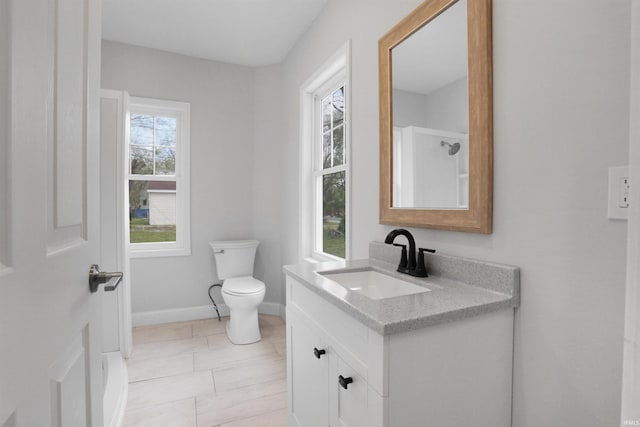 bathroom featuring toilet, vanity, and baseboards