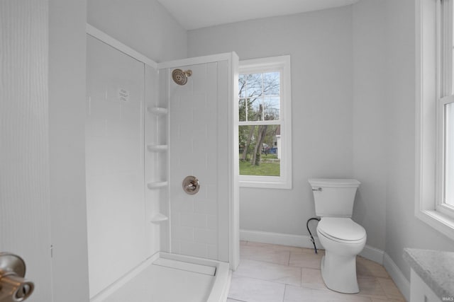bathroom with walk in shower, toilet, and baseboards