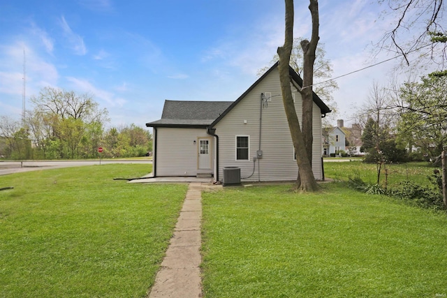 back of property featuring a lawn, roof with shingles, and cooling unit