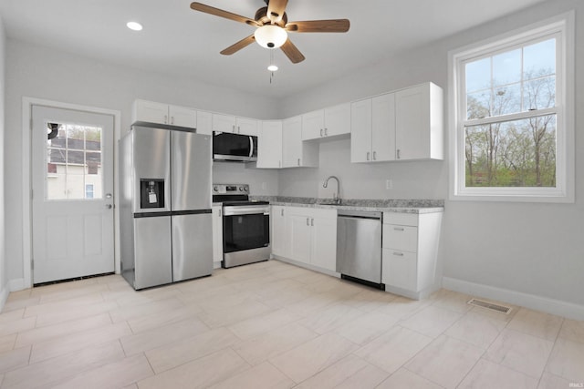 kitchen with stainless steel appliances, visible vents, white cabinetry, a sink, and ceiling fan