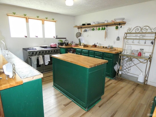 kitchen featuring light wood finished floors, wood counters, green cabinetry, and double oven range