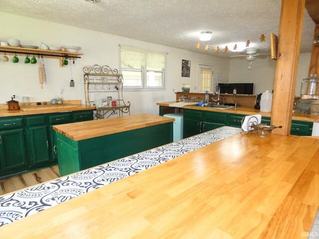 kitchen featuring green cabinetry, butcher block countertops, and a textured ceiling