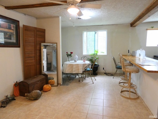 dining room with beamed ceiling, a textured ceiling, ceiling fan, and light tile patterned floors