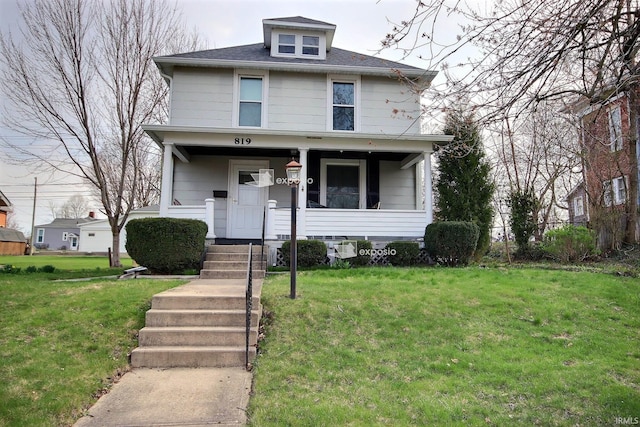 american foursquare style home featuring a porch and a front lawn
