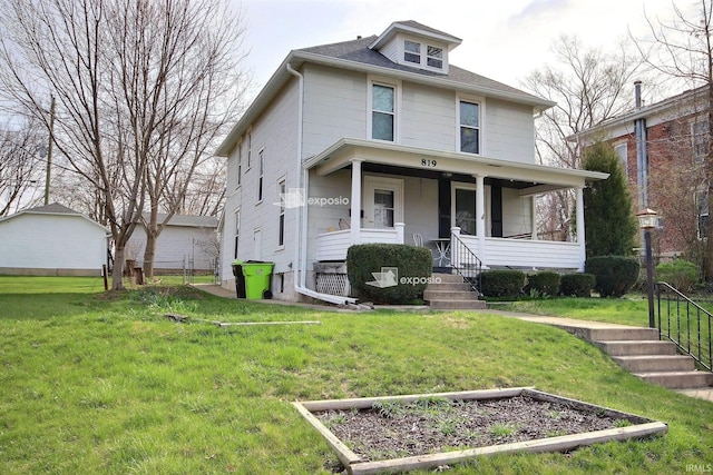american foursquare style home with a porch, a vegetable garden, and a front lawn
