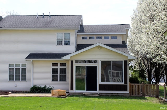 back of house with fence, a shingled roof, a sunroom, and a yard