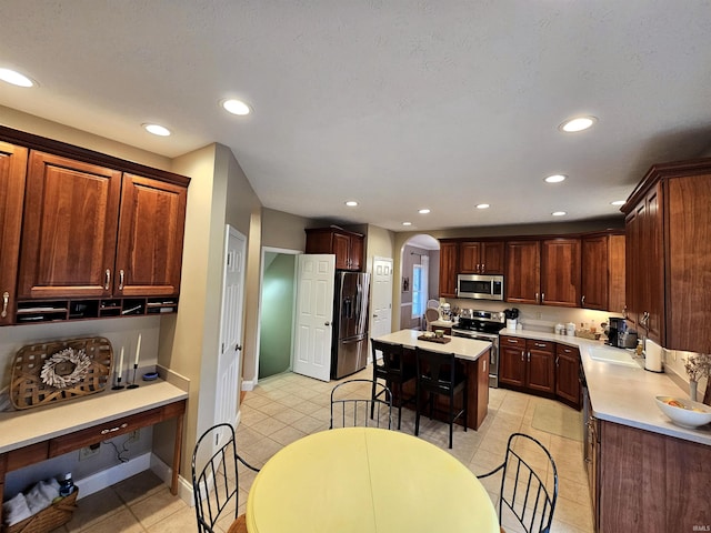 kitchen featuring arched walkways, appliances with stainless steel finishes, light countertops, and recessed lighting