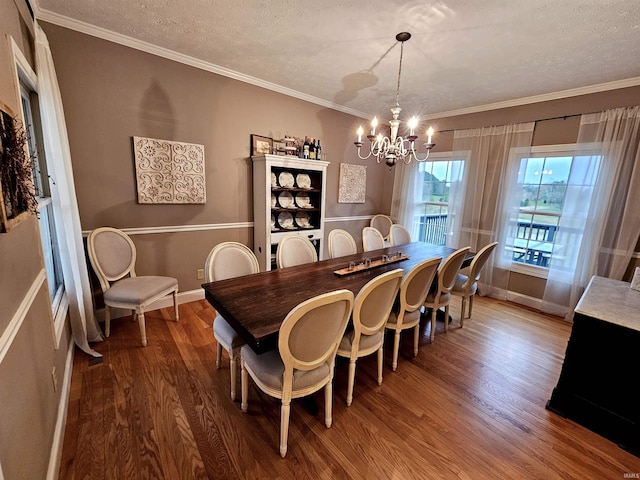 dining area featuring wood finished floors, a textured ceiling, baseboards, and a notable chandelier