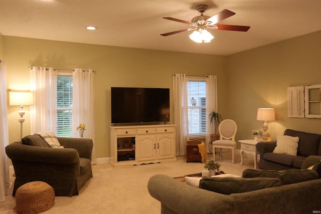 living room with a healthy amount of sunlight, a ceiling fan, baseboards, and light carpet