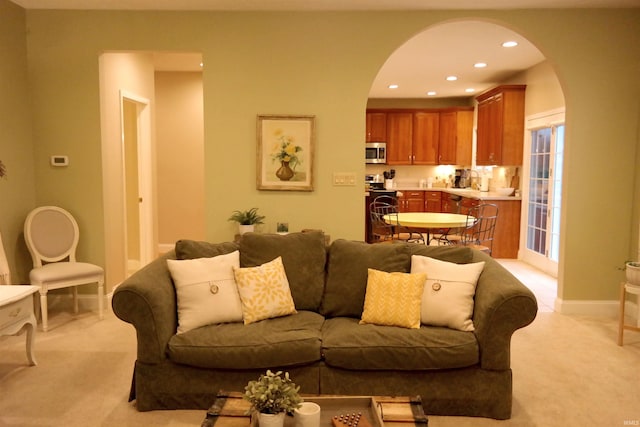 living room with arched walkways, light colored carpet, and recessed lighting