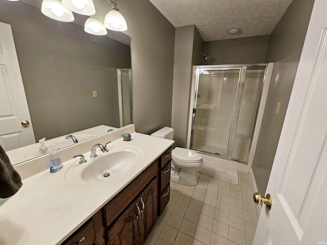 bathroom with tile patterned floors, a textured ceiling, toilet, a stall shower, and vanity