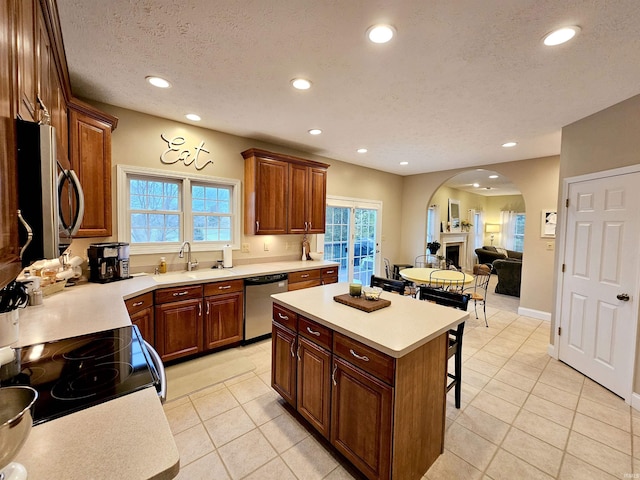 kitchen with recessed lighting, stainless steel appliances, a sink, arched walkways, and a breakfast bar area