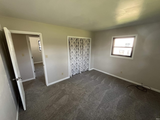 unfurnished bedroom with baseboards and dark carpet