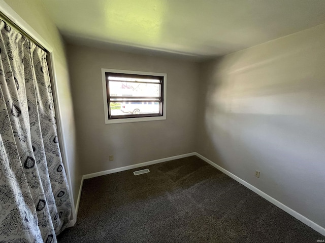 unfurnished bedroom featuring dark carpet, baseboards, and visible vents
