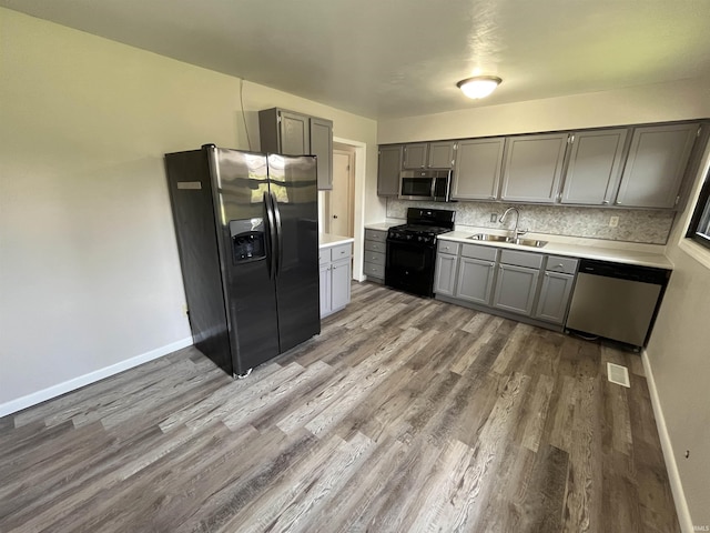 kitchen with wood finished floors, gray cabinets, stainless steel appliances, and a sink