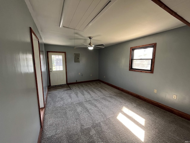 carpeted spare room featuring attic access, baseboards, a ceiling fan, and electric panel