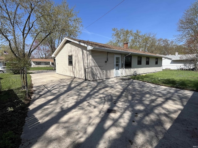 back of house featuring a chimney, fence, a yard, a patio area, and driveway