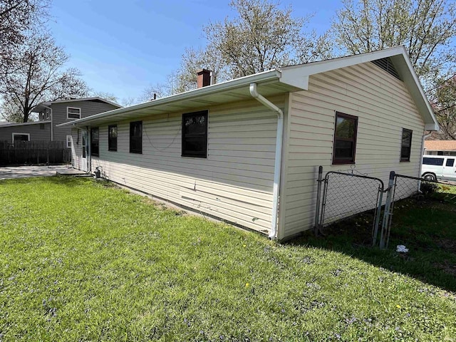 view of side of home featuring fence, a lawn, and a chimney