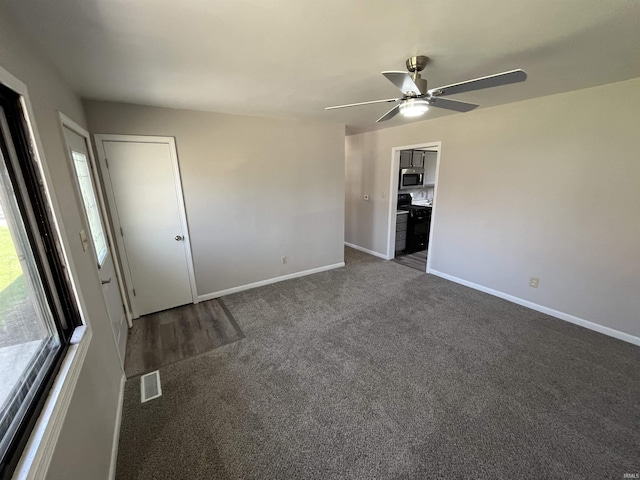 unfurnished bedroom featuring dark carpet, visible vents, a ceiling fan, and baseboards