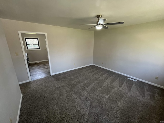 unfurnished room featuring visible vents, a ceiling fan, baseboards, and dark colored carpet