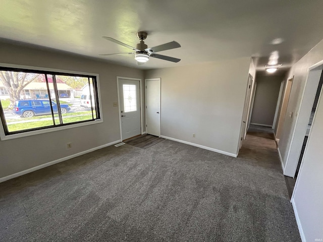 spare room with a ceiling fan, baseboards, and dark carpet