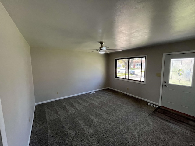 entryway with dark colored carpet, visible vents, baseboards, and ceiling fan