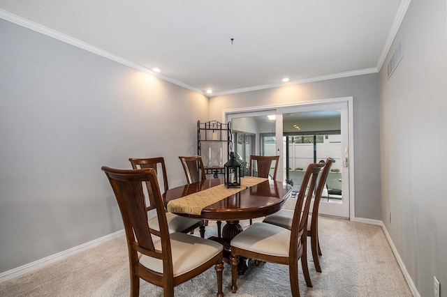 dining room featuring visible vents, baseboards, ornamental molding, and light carpet