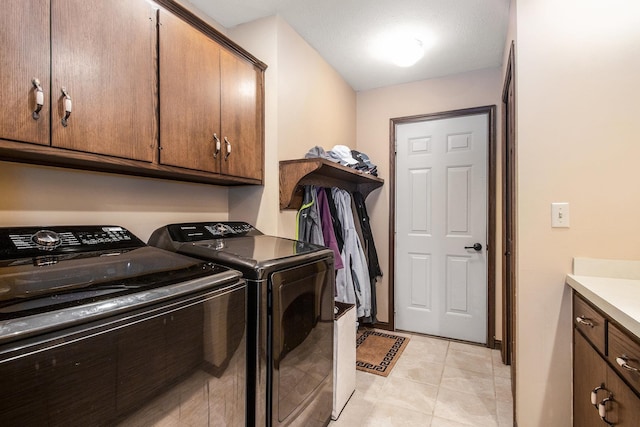 clothes washing area with light tile patterned floors, cabinet space, and washer and clothes dryer