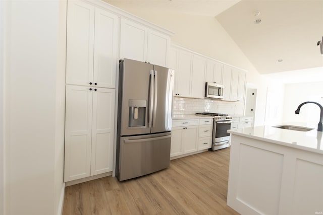 4026 W Carmola Dr, Bloomington, IN 47404 - kitchen featuring stainless steel appliances, backsplash, light countertops, a sink, and light wood-type flooring