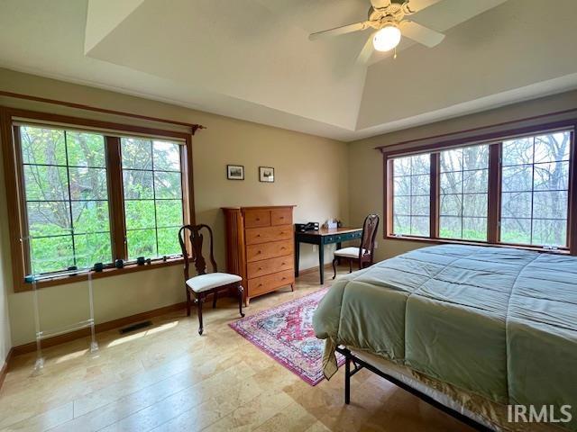 bedroom featuring vaulted ceiling, ceiling fan, baseboards, and multiple windows