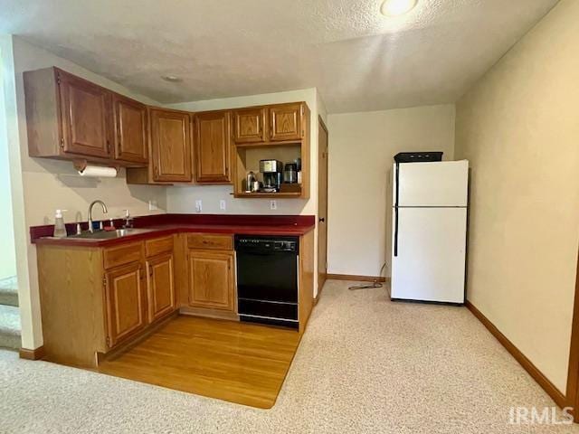 kitchen featuring light carpet, a sink, dark countertops, freestanding refrigerator, and dishwasher