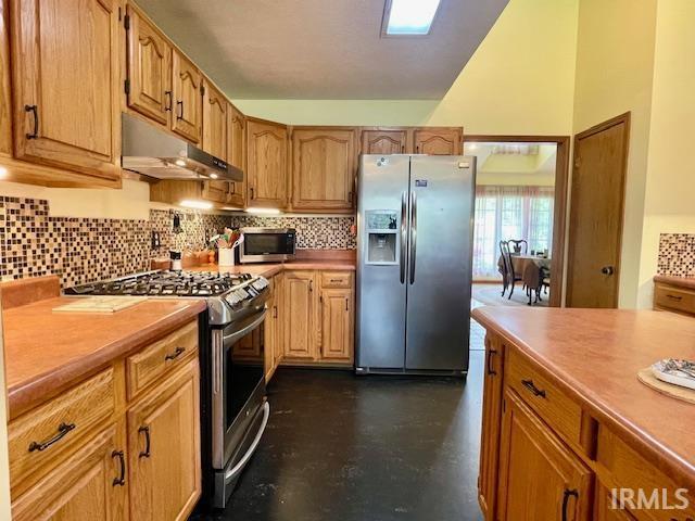 kitchen featuring backsplash, under cabinet range hood, light countertops, and stainless steel appliances