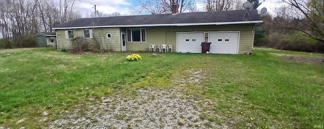 rear view of house featuring a lawn, driveway, and a garage