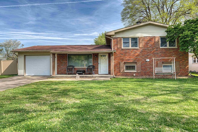 split level home featuring driveway, covered porch, an attached garage, a front yard, and brick siding