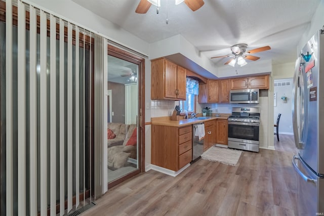 kitchen featuring light wood-type flooring, ceiling fan, a sink, and appliances with stainless steel finishes
