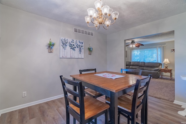 dining area with wood finished floors, visible vents, baseboards, and ceiling fan with notable chandelier