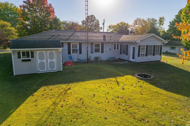 back of property with a lawn, central AC unit, an outdoor structure, and a storage unit