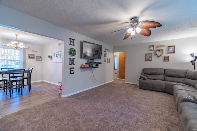 carpeted living room featuring visible vents, a textured ceiling, baseboards, and ceiling fan with notable chandelier