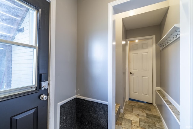 doorway featuring stone finish floor and baseboards